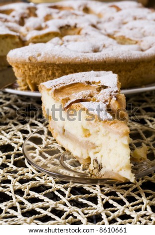 One piece of fruit pie on a saucer, the whole pie is on background. On wattled straw cloth. Close-up to a viewer.
