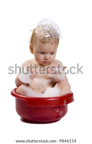 Cute bating child in red wash-basin with bubble bath on his head and body, isolated. See the whole series in my portfolio