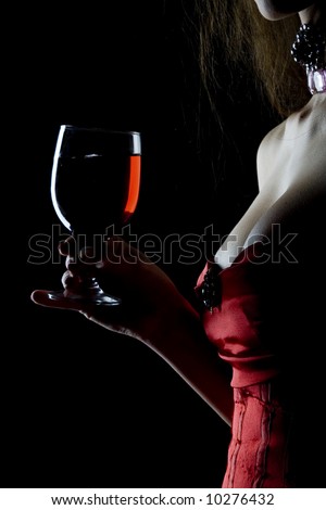 Pretty tempting and sexy decollete woman in red corsage with wineglass full of red drink (wine, juice)
