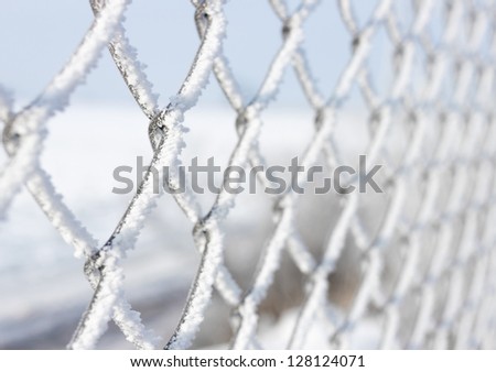 Macro close-up of metal fence covered with frozen snow