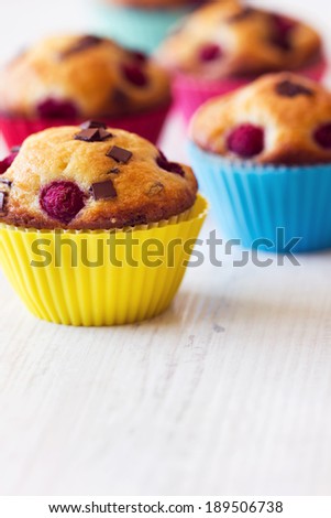 Group of tasty colored muffins placed on wooden white table. Focus in foreground.