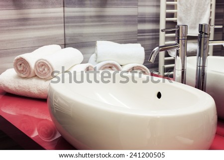 Modern white oval sink in bathroom. Clean white towels in the background.