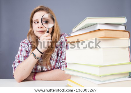funny teenager searching something between pile of books