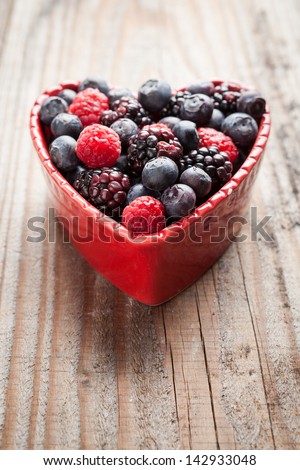 Heart of red fruit on wooden background