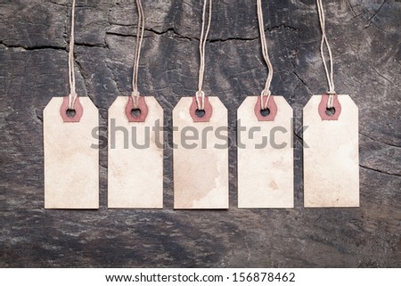 Assortment of vintage tags and labels with texture and stain details. Wood background