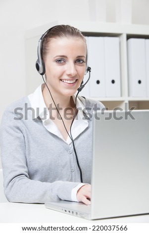 Close-up portrait of young smiling business woman with headset
