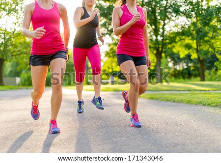 group of healthy girls running outdoors at sunset with lens flare.