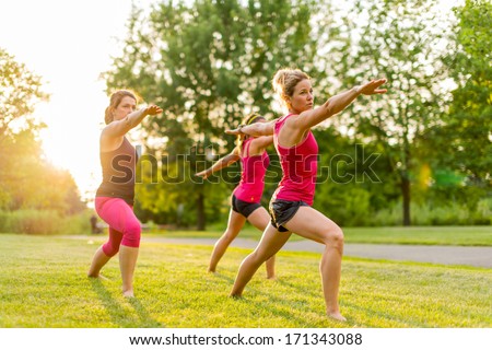 Horizontal Group Of Women Doing The Warrior Yoga Pose Outdoors At Sunset With Lens Flare