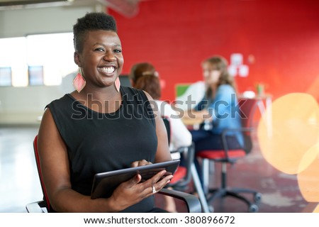 Confident female designer working on a digital tablet in red creative office space