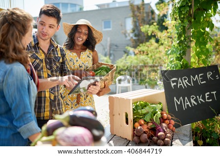 Friendly woman tending an organic vegetable stall at a farmer\'s market and selling fresh vegetables from the rooftop garden