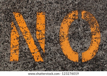 A worn and yellow \'No\' sign stenciled on a  pavement
