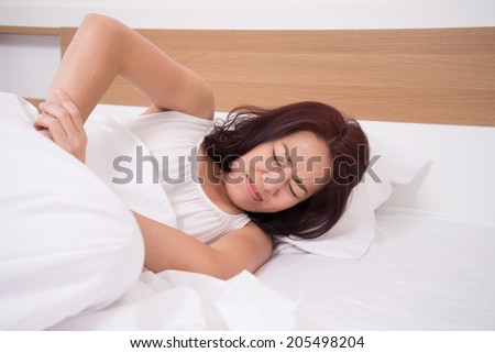 sick woman on bed concept of stomachache, headache, hangover or insomnia