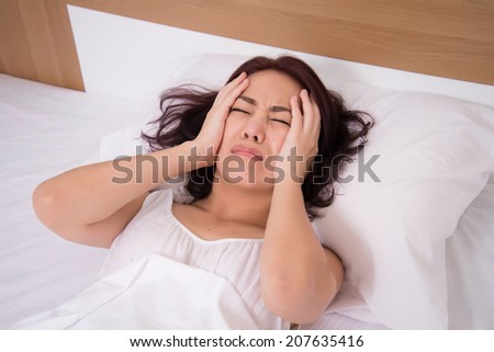 sick woman on bed concept of stomachache, headache, hangover or insomnia