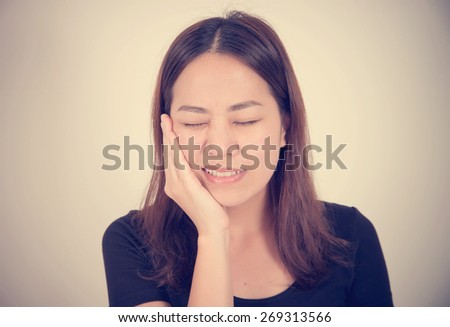 Woman suffering toothache with hand on face isolated on a white background with vintage filter effect