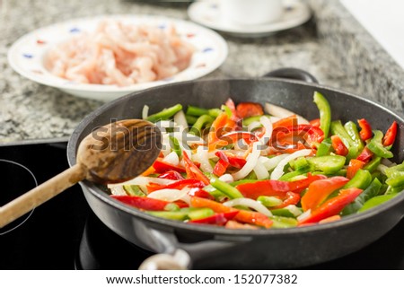 Closeup of female cooking vegetables and chicken for a mexican food in a black pan