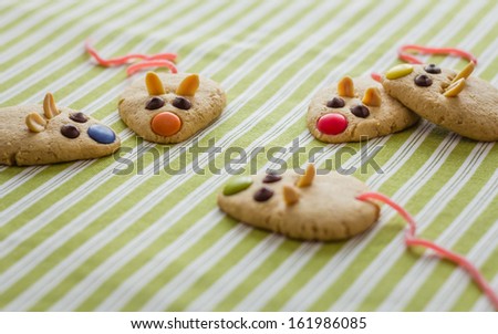 Cookies with mouse shaped and red licorice tail over green striped tablecloth