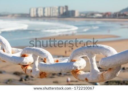 Closeup of metal chain fence over city beach background