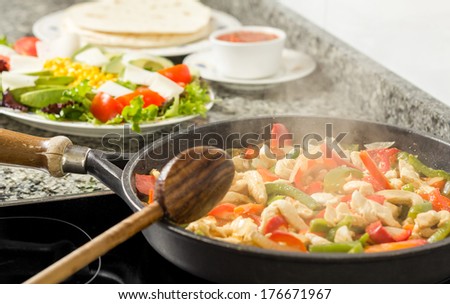 Closeup of black pan cooking vegetables and chicken for a mexican food in the kitchen