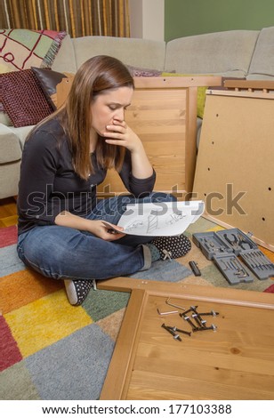 Concentrated girl with tools reading the instructions to assemble a new furniture for home