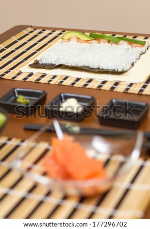 Japanese sushi ready to roll with rice, avocado and shrimps on nori seaweed sheet