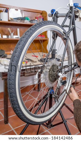 Real bicycle mechanic repairing black custom fixie bike in the workshop