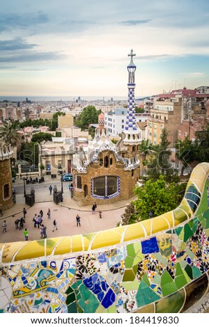 BARCELONA, SPAIN - MAY 31, 2013: Famous colorful ceramic mosaic bench of park Guell, with entrance pavilion on the background and designed by Antonio Gaudi