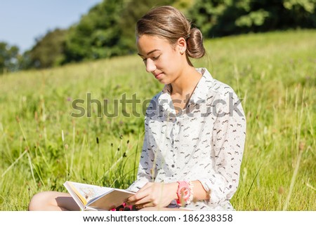 Portrait of beautiful young student reading a book in the school park