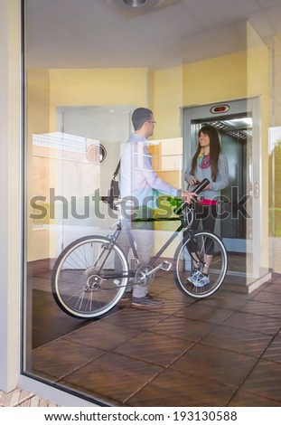 Handsome casual business man and beautiful girl with sportswear speaking in a office hall entrance behind the glass wall