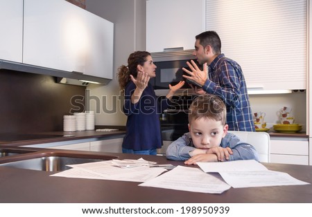 Sad child suffering and his parents having hard discussion in a home kitchen by couple difficulties. Family problems concept.
