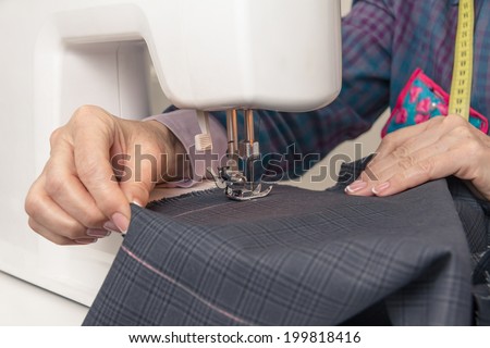 Closeup of seamstress hands working with clothing item on a sewing machine