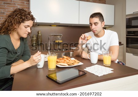 Serious and bored young couple having a breakfast in the home kitchen