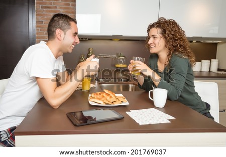 Happy young love couple speaking and having a good breakfast in the home kitchen