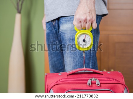 Man checking hand luggage weight using a steelyard balance by low cost airlines restrictions