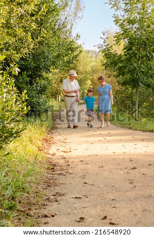 Front view of grandparents and grandchild walking on a nature path
