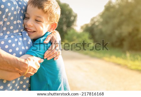 Portrait of happy grandson hugging grandmother over a nature outdoor background