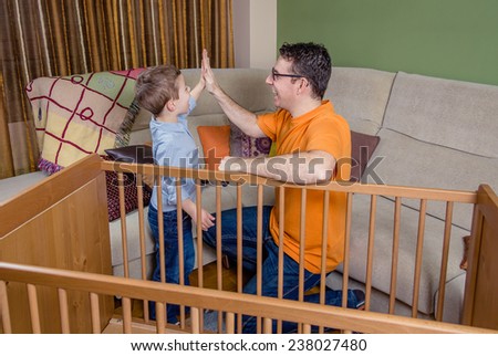 Portrait of father and son giving five for a success in the assembly of cot for a newborn at home. Family leisure concept