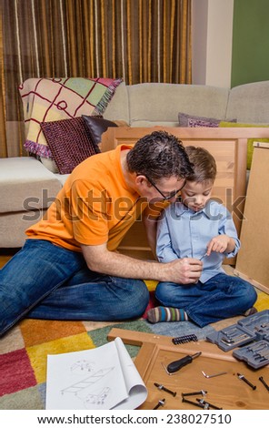 Portrait of father and son assembling with tools a new furniture for home. Family leisure concept