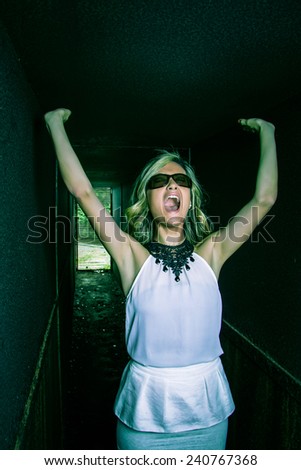 Portrait of scared beautiful young girl screaming alone inside of a metallic dark tunnel