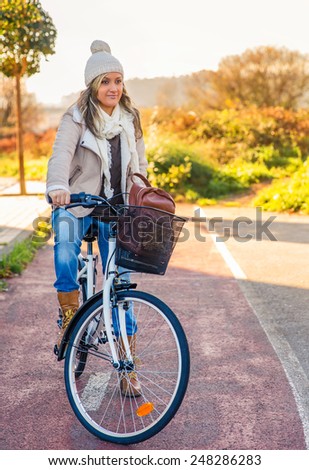 Portrait of beautiful young woman stit over bicycle in a street bike lane on sunny winter day