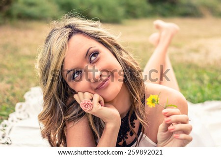 Portrait of romantic young woman with a yellow flower in the hand dreaming. Relax outdoor time concept.