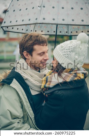 Portrait of young beautiful couple embracing under the umbrella in an autumn rainy day. Love and couple relationships concept.