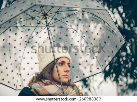 Closeup of young beautiful girl under a umbrella in an autumn rainy day
