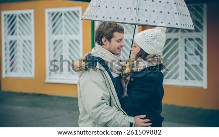 Portrait of young beautiful couple embracing under the umbrella in an autumn rainy day. Love and couple relationships concept.