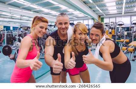 Group of friends with thumbs up smiling on a fitness center after hard training day