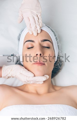 Closeup of pretty woman getting cosmetic injection in the face like a part of the clinic treatment. Medicine, healthcare and beauty concept.