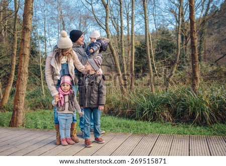 Portrait of happy family enjoying together leisure over a wooden pathway into the forest. Family time concept.