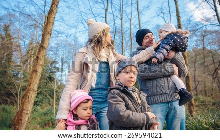Portrait of happy family enjoying together leisure over a wooden pathway into the forest. Family time concept.