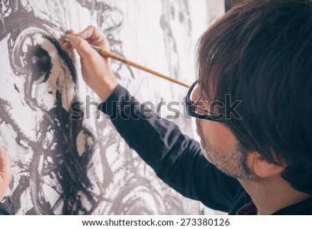 Closeup of painter artist working in a modern abstract oil canvas in his studio