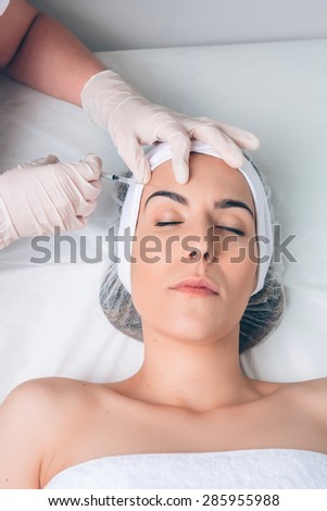 Young pretty woman getting cosmetic injection in the face like a part of the clinic treatment. Medicine, healthcare and beauty concept.