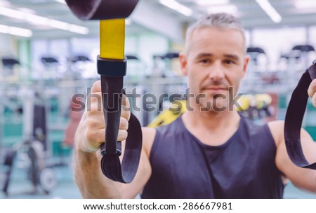 Closeup of fitness strap in the hand of man doing hard suspension training in a fitness center. Healthy and sporty lifestyle concept.
